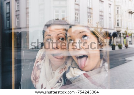 Close up lifestyle portrait of girls best friends makes funny grimaces on camera , show tongue and laughing together. Happy friendship concept with young people having fun together and enjoying it. 