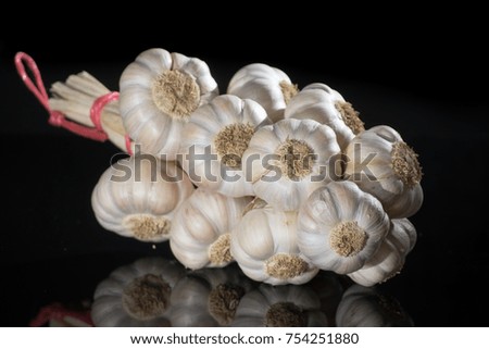 String of french pink garlic on old tin plate on black background with reflection close up