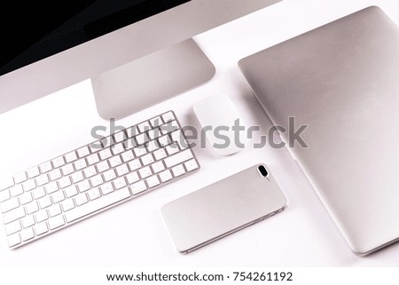 Modern workplace with metallic pc with keyboard and mouse, mobile phone, metalic laptop lying on a desk isolated on white background.