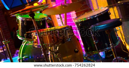 Percussion Musical instruments. Beautifu music background. Drum set on the stage in multicolored rays of concert light closeup with selective focus. Colorful Wide Screen Wallpaper or Web Banner