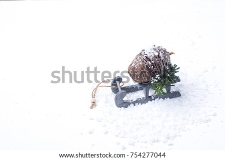 cone on a wooden sled in the snow on a white background