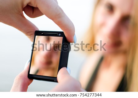 woman holds a new action camera in her hands and takes off a girl model