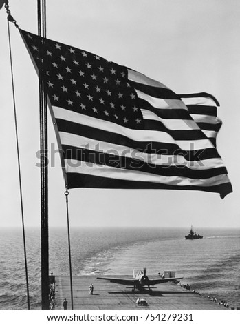 Flag of the United States snaps in the breeze over the USS Santee. November 1942. USS Santee was one of 4 escort carriers in Operation Torch, the Nov. 1942 Allied invasion of North Africa. Photo by Ho