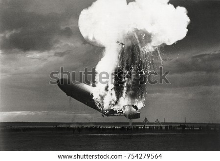 Left side view of German airship 'Hindenburg' burning, at Lakehurst, N.J., May 6, 1937. Hindenburg used flammable hydrogen for lift, which incinerated the airship in a massive fireball in less than 30 Royalty-Free Stock Photo #754279564