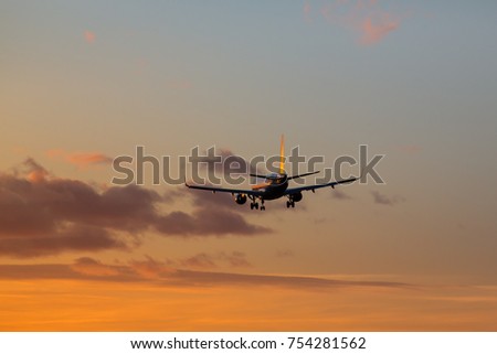 Airplane is landing at airport during a wonderful dramatic sunset / Wide-body modern passenger airplane almost landed at airport / Vacation, aviation, travel, trip  concept
