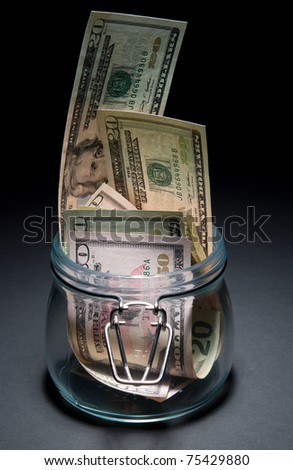 Dollars in glass jar on black