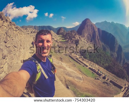 Man tourist backpacker take photo selfie with Machu Picchu, a Peruvian Historic Sanctuary and UNESCO World Heritage Site and one of the New Seven Wonders of the World