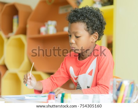 American boy make home wore drawing color pencils in kindergarten classroom, preschool library and kid education concept, Vintage effect style pictures.