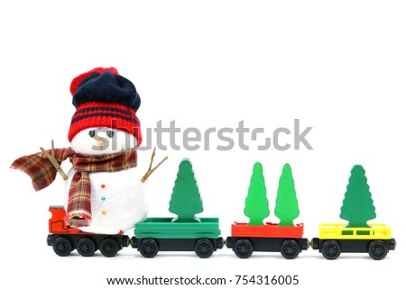 Snowman doll wear red and black knitting wool beanie hat and brown plaid scarf. Snowman sit on the red wooden train. Four wooden green christmas trees put on the green, red and yellow wooden train toy