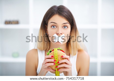 Diet. Portrait woman wants to eat a Burger but stuck skochem mouth, the concept of diet, junk food, willpower in nutrition Royalty-Free Stock Photo #754317718