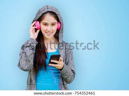 Portrait of beautiful girl in hood with smart phone listening to music from headphones