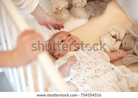 Newborn cute baby lies in the crib and looking at mother