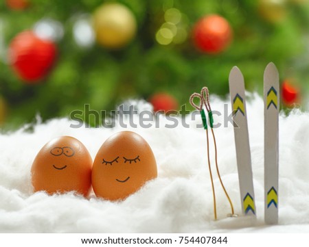 Funny lovely eggs with ski in snow over christmas tree background