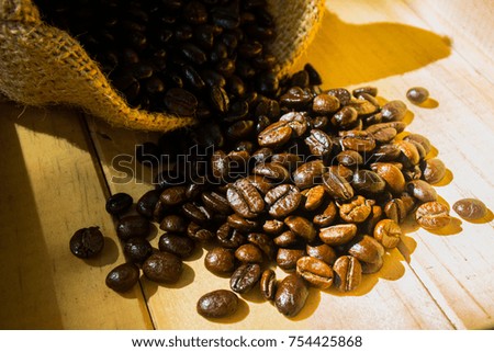 Roasted coffee beans in a small canvas bag - on a wooden table background.