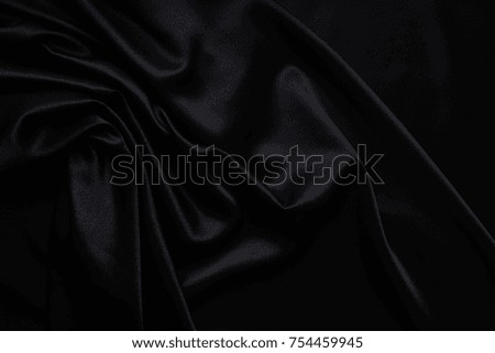 Dark black silky, satin fabric, wave, draperies. Beautiful textile backdrop to create creative layouts for black Friday. Close-up. Top view