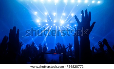 Happy people dance in nightclub party concert and listen to the music from DJ on the stage in the background.