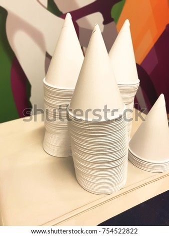Cone shape disposable paper cups above water tank.Cone shape disposable paper cups on cooler water dispenser machine.
