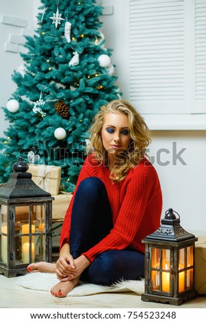 Christmas room with beautiful blonde girl, lantern and gifts, Christmas tree. Home holiday background