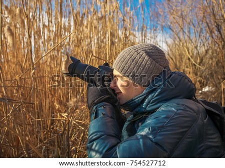 Closeup of photographer with digital camera outdoors. Young man photographs nature.