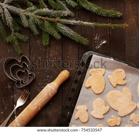 Christmas cookies on a baking sheet on wooden background with Christmas tree