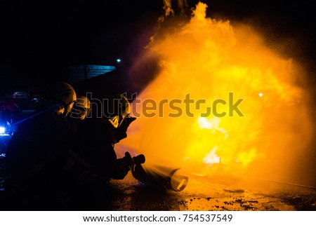 Fireman using extinguisher and water from hose for fire fighting at firefight training of insurance group. Firefighter wearing a fire suit for safety under the danger case.