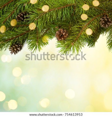 Christmas background with copy space. Christmas tree branches border with golden confetti. Arrangement of fresh green pine branches with cones on light yellow green background, top view