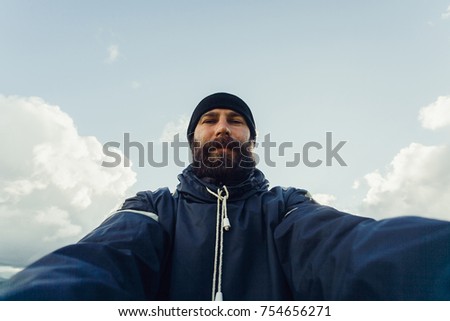 tourism, mountains, lifestyle, nature, people, Selfie concept - Young Man Traveler Makes Selfie On Background Mountains In Summer, at sunset. bearded tourist smiling