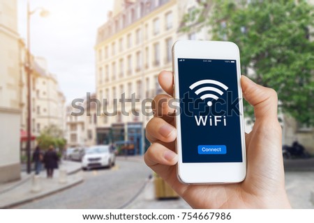 Connection to public WiFi hotspot in the city street to access internet on smartphone, concept about wireless technology and travel, close-up of hand Royalty-Free Stock Photo #754667986
