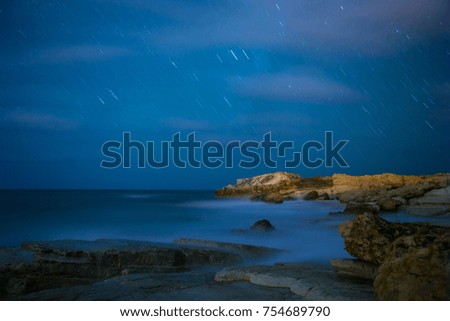 Long exposure. Sea and waves. Rocky coast. Night starry sky.