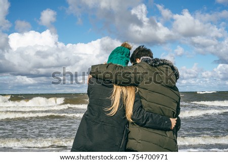 a young couple in love spending weekends on the coast of the cold Baltic sea, sandy beach, warm jackets, family weekend man and woman running on the beach.