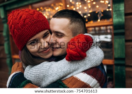 Close up portrait of young couple in knitted clothes in winter with christmas light background