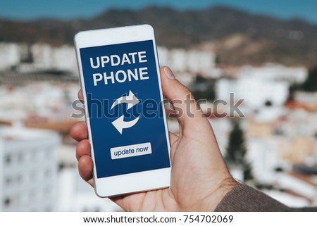 Man holding mobile phone with "Update phone" notification in the screen.