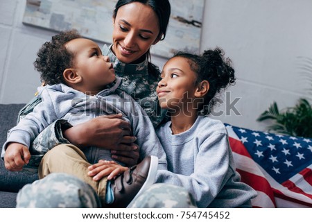 african american mother in military uniform sitting with her children, american flag on background
