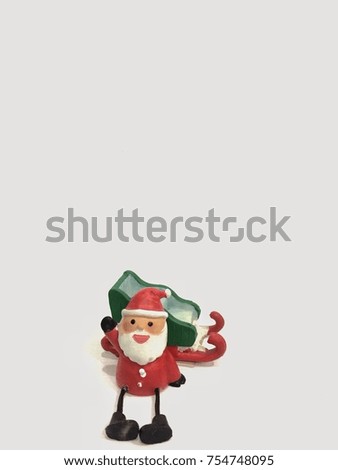 A small Santa Claus model sitting next to a green slate with his hand waving and white background with empty space for texts.