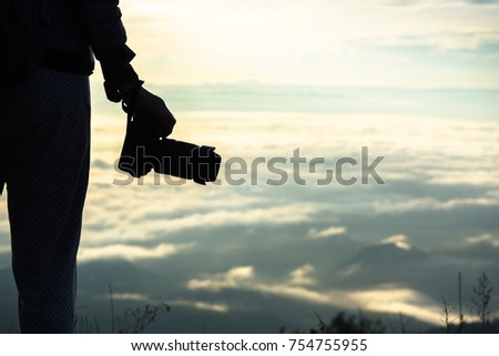 silhouette woman holding camera on the beautiful morning landscape.