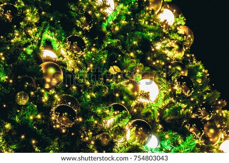Abstract Christmas gold bokeh lights with golden ball decoration on Christmas tree background. place for text concept. Beautiful Festive textured background. Vintage defocused on red floor background