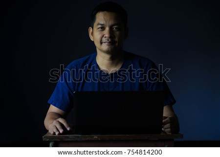 Portrait of asian man play laptop in dark room , Low key style.
