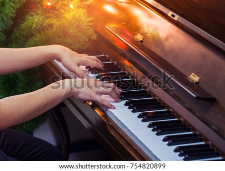 close up of man hands plays  on  Piano Keys with Christmas tree and decoration light, in the night of Christmas season, Christmas backgroumd with copy space