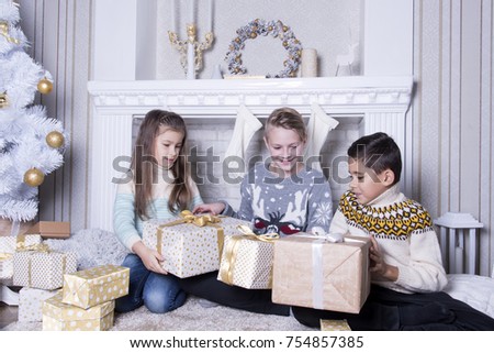 Group of three children. Merry Christmas and Happy Holidays concept. Family holiday. New Year's picture of brothers and sister. Children opening a gift at home. Friends are interested and amazed. 