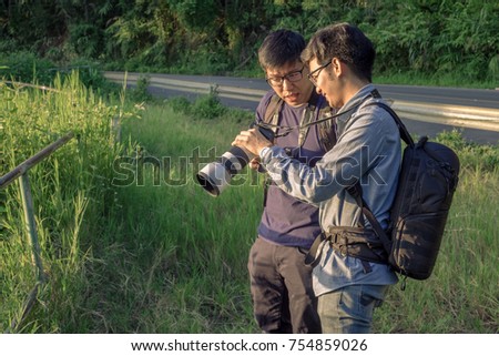 two Asia photo stock contributors  travel in Asia. hand holding pro digital camera with telephoto lenses. photo trip with friend, Share trick and tips and knowledge together.helping teaching friend 