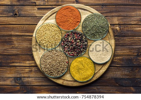 Top view of glass bowls with different spices on a wooden board