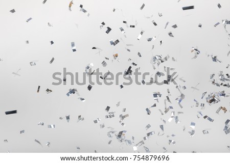 Falling silver confetti pieces on gray
