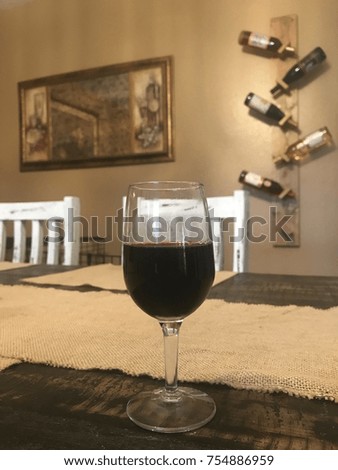 Full bodied red wine on wooden table with wine rack in the background.