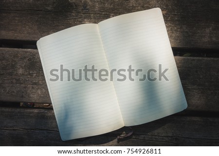 Blank empty moleskine notepad see from top on wooden table in a park