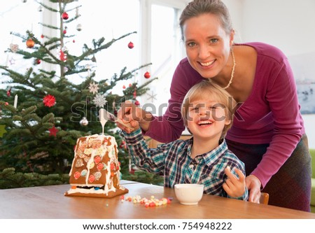 mother, boy decorating gingerbread house