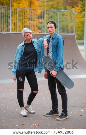 Young guy and girl skateboarders, outdoors on a bright autumn day.