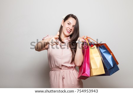 Happy cute girl stands carrying present bags boxes