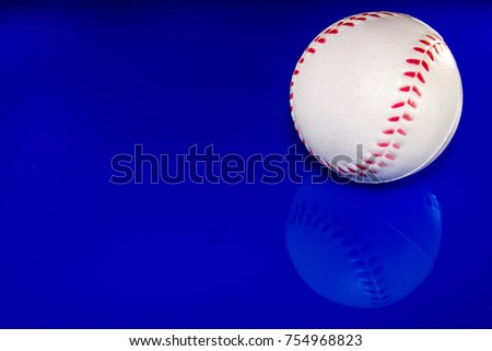 A closeup of a baseball against a reflective blue background.