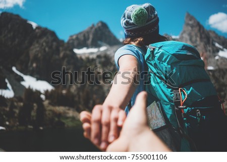 Young active hiking couple with backpacks taking photo, woman guiding by the hand into mountain wilderness