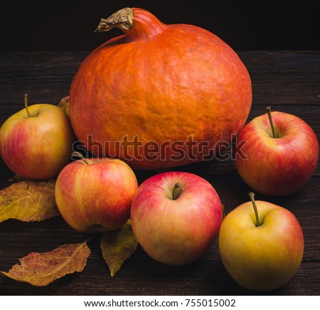 Still life with pumpkins, apples in the basket and autumn leaves at wooden background.